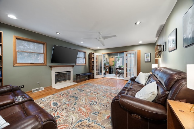 living room with plenty of natural light, wood finished floors, visible vents, and a high end fireplace