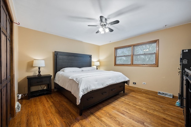 bedroom with a ceiling fan, baseboards, visible vents, and light wood finished floors