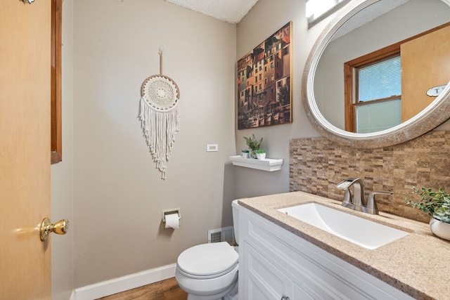 half bath with tasteful backsplash, baseboards, toilet, wood finished floors, and vanity