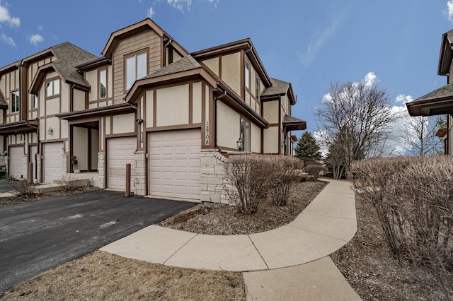 view of front facade with a garage, a shingled roof, driveway, stone siding, and stucco siding