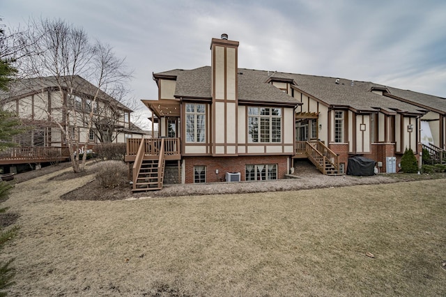 rear view of house with central air condition unit, a shingled roof, stairway, stucco siding, and a chimney