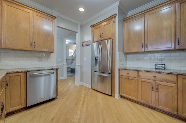 kitchen featuring ornamental molding, stainless steel appliances, light wood finished floors, and light stone counters