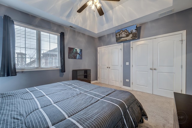 bedroom with light carpet, two closets, visible vents, and baseboards