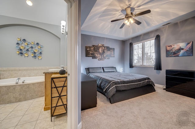 bedroom with carpet, a raised ceiling, visible vents, a ceiling fan, and tile patterned floors