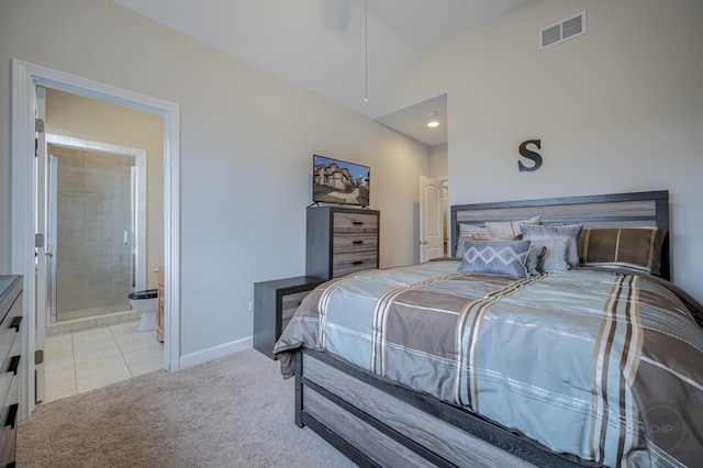 bedroom featuring baseboards, visible vents, light colored carpet, ensuite bathroom, and vaulted ceiling