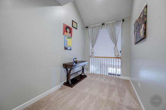 corridor featuring carpet flooring, vaulted ceiling, and baseboards