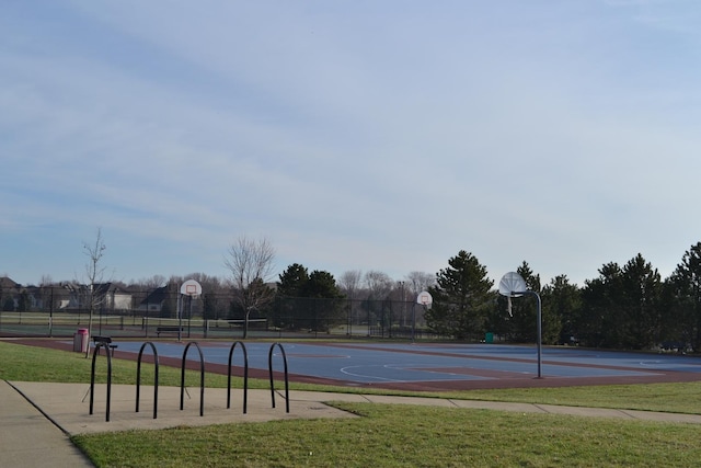 view of basketball court with community basketball court, fence, and a lawn