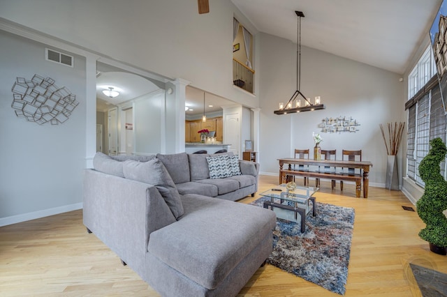 living room featuring a chandelier, high vaulted ceiling, light wood-type flooring, and visible vents