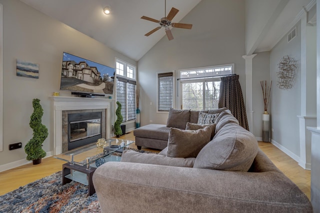 living area with high vaulted ceiling, a tile fireplace, visible vents, and wood finished floors