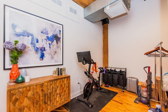 exercise room featuring visible vents, baseboards, and wood finished floors