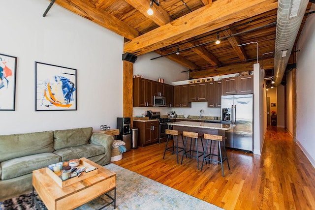 living area featuring wood ceiling, a high ceiling, wood finished floors, and beamed ceiling