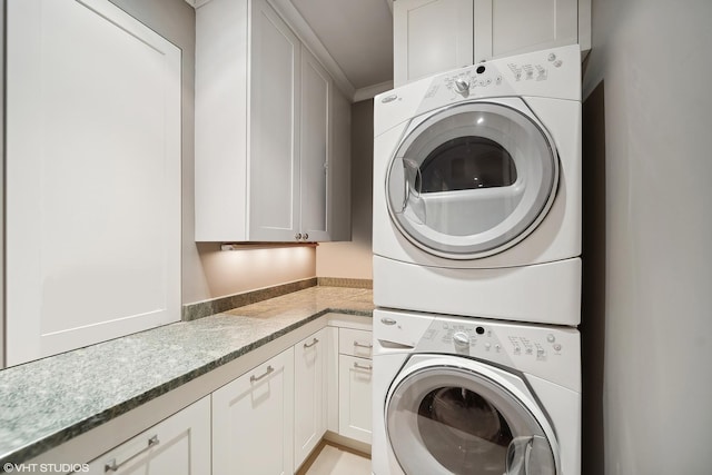 washroom featuring cabinet space and stacked washer and clothes dryer