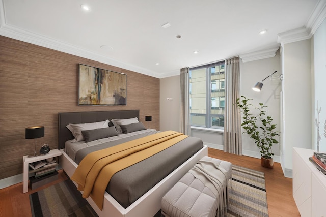 bedroom featuring an accent wall, light wood-type flooring, and ornamental molding