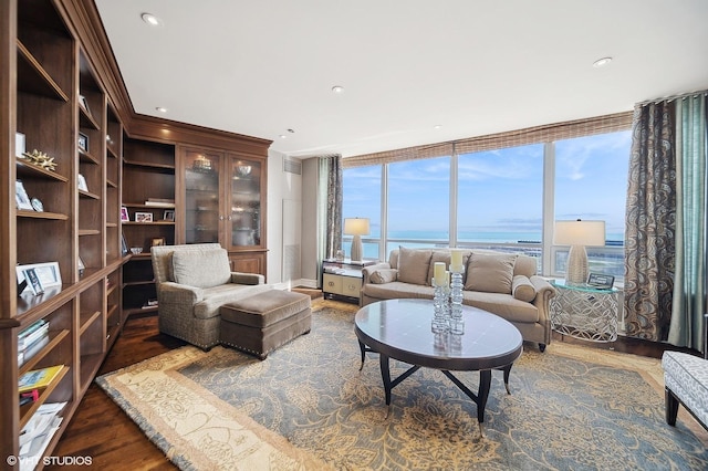 living area with crown molding, recessed lighting, a water view, wood finished floors, and a wall of windows