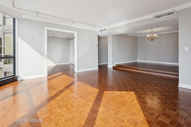 spare room featuring visible vents, track lighting, an inviting chandelier, crown molding, and baseboards