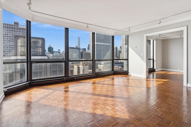 spare room with baseboards, plenty of natural light, rail lighting, a city view, and crown molding