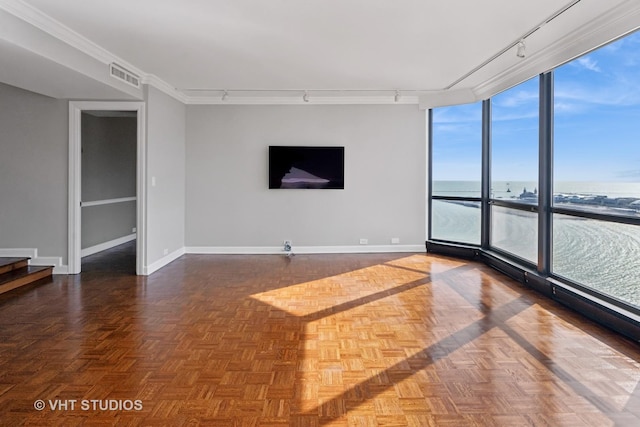 unfurnished living room featuring visible vents, track lighting, crown molding, baseboards, and expansive windows