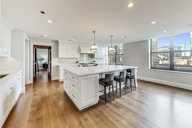 kitchen featuring a view of city, backsplash, white cabinetry, range, and custom exhaust hood