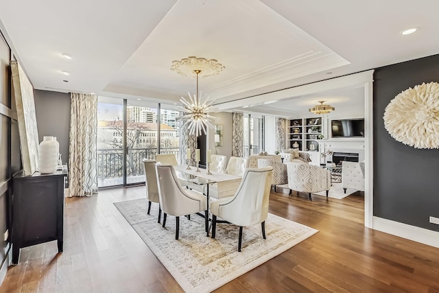 dining room with a notable chandelier, a raised ceiling, and wood finished floors