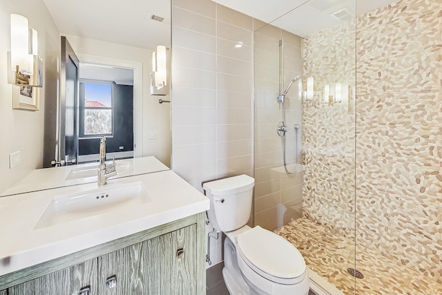 full bathroom featuring visible vents, toilet, vanity, and a tile shower