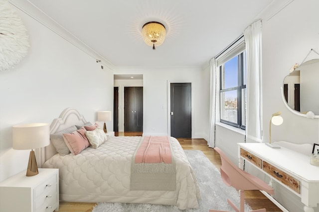 bedroom featuring baseboards, light wood-style flooring, and ornamental molding