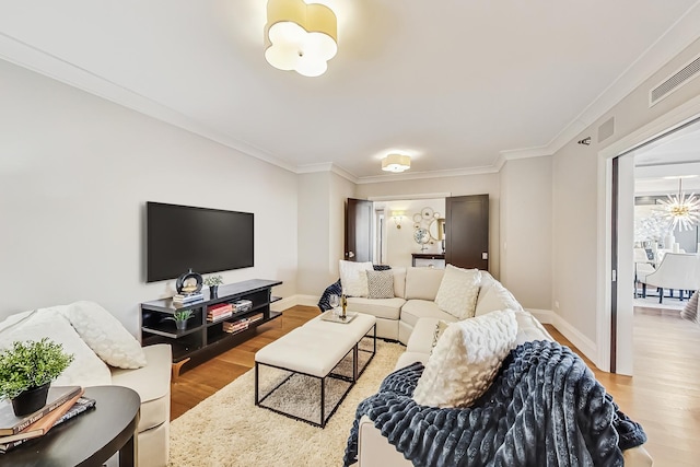 living area featuring visible vents, ornamental molding, baseboards, and wood finished floors