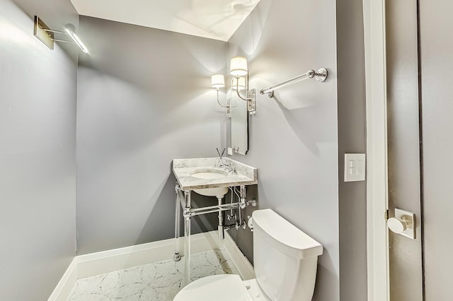 half bathroom featuring a sink, baseboards, and toilet