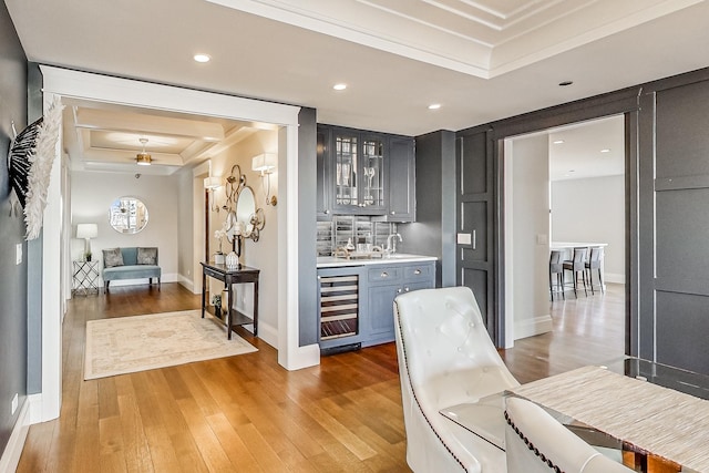 interior space featuring recessed lighting, wine cooler, light wood-style floors, indoor wet bar, and a raised ceiling