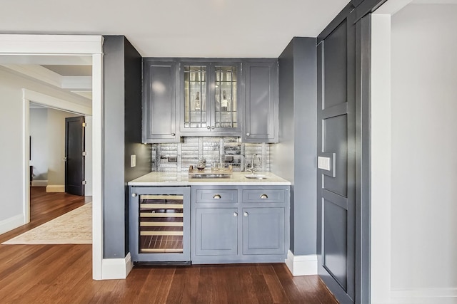 bar with a sink, decorative backsplash, dark wood-type flooring, wine cooler, and indoor wet bar