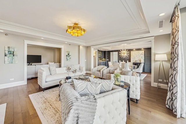 living area with visible vents, baseboards, light wood-type flooring, recessed lighting, and a raised ceiling