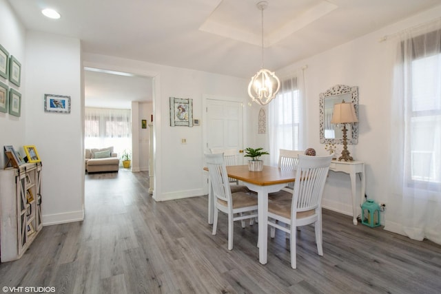 dining space featuring baseboards, a tray ceiling, a chandelier, and wood finished floors