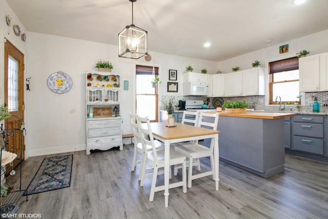 kitchen featuring white appliances, white cabinets, decorative backsplash, butcher block counters, and a healthy amount of sunlight