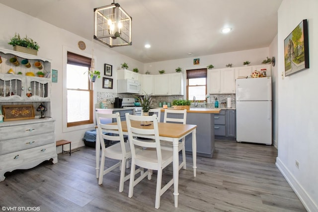 kitchen with white appliances, a kitchen island, light countertops, and backsplash