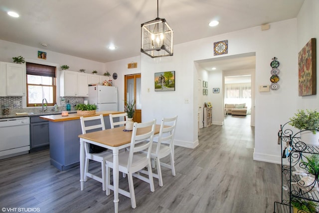 dining area featuring recessed lighting, baseboards, light wood finished floors, and an inviting chandelier