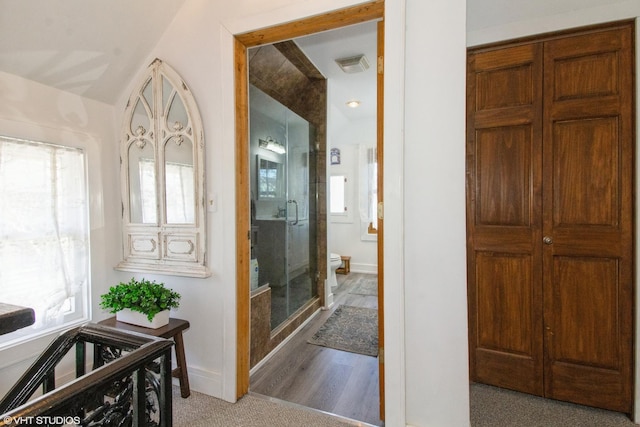 bathroom with lofted ceiling, visible vents, toilet, a stall shower, and baseboards