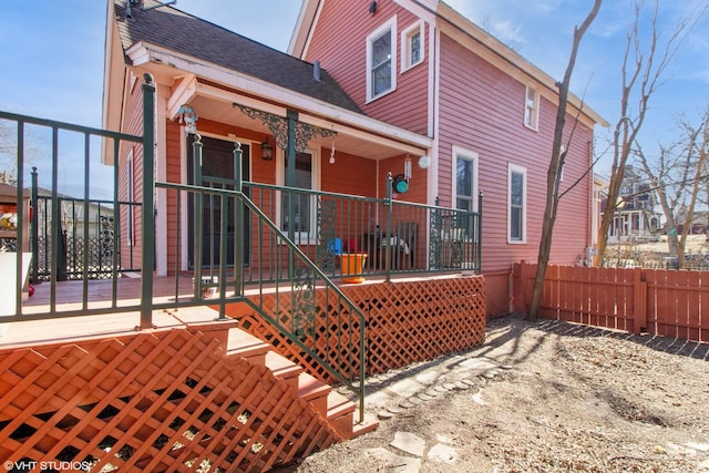 back of house featuring a shingled roof and fence