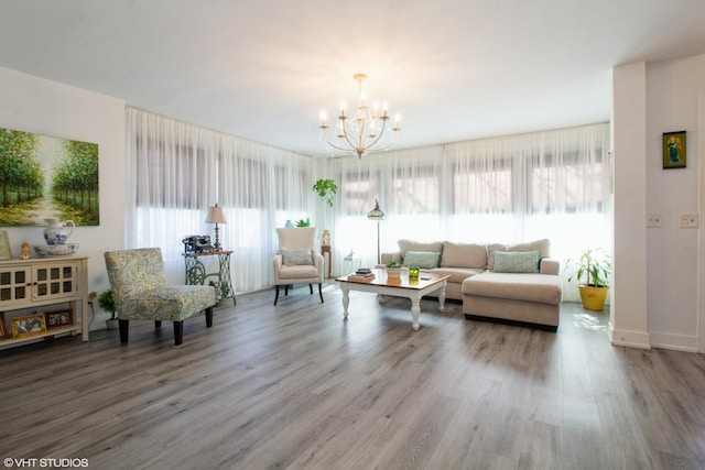 living area featuring a notable chandelier, plenty of natural light, baseboards, and wood finished floors