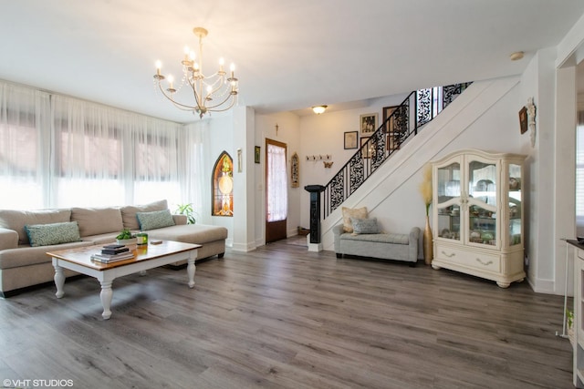 living area featuring an inviting chandelier, baseboards, stairway, and wood finished floors