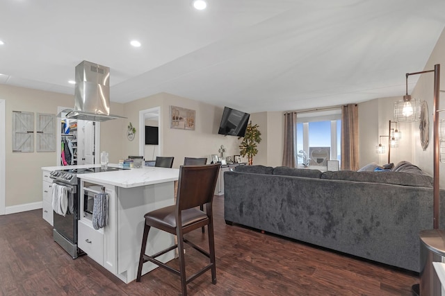 kitchen featuring a breakfast bar, dark wood-style flooring, open floor plan, stainless steel electric range oven, and island exhaust hood