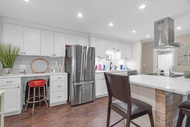 kitchen with black electric stovetop, dark wood-type flooring, freestanding refrigerator, island range hood, and a kitchen breakfast bar