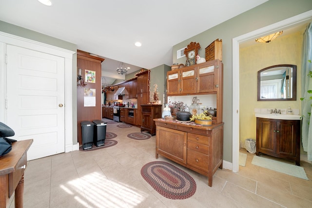 interior space featuring light tile patterned floors, baseboards, an inviting chandelier, a sink, and recessed lighting