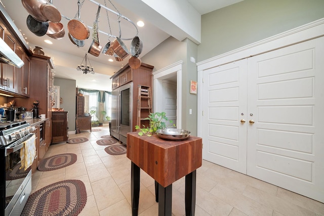 kitchen featuring light tile patterned floors, dark brown cabinetry, gas range, and recessed lighting