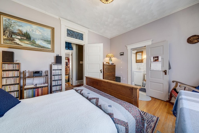 bedroom featuring light wood-type flooring, vaulted ceiling, crown molding, and ensuite bathroom