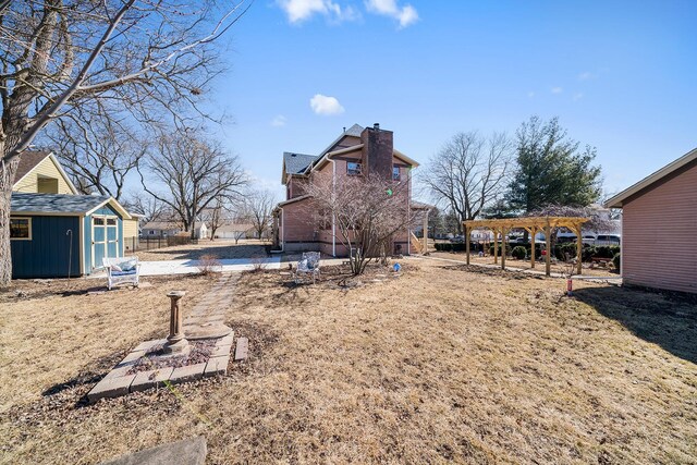 view of yard featuring an outdoor structure, fence, a storage shed, and a pergola