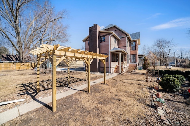 exterior space with fence, a chimney, and a pergola