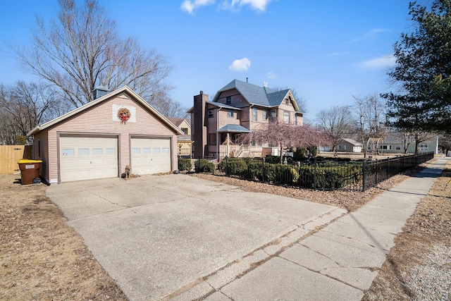 view of front facade featuring an outbuilding, a fenced front yard, and a detached garage