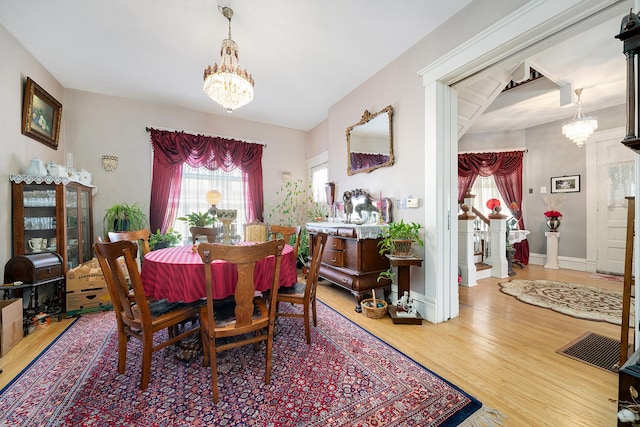 dining area featuring baseboards, wood finished floors, and an inviting chandelier