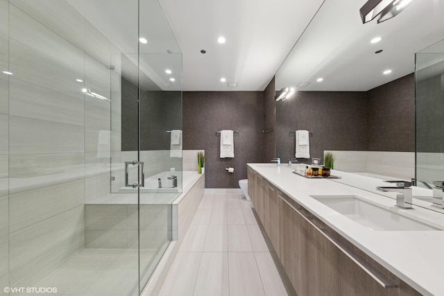 bathroom featuring toilet, a sink, a shower stall, tile patterned floors, and double vanity