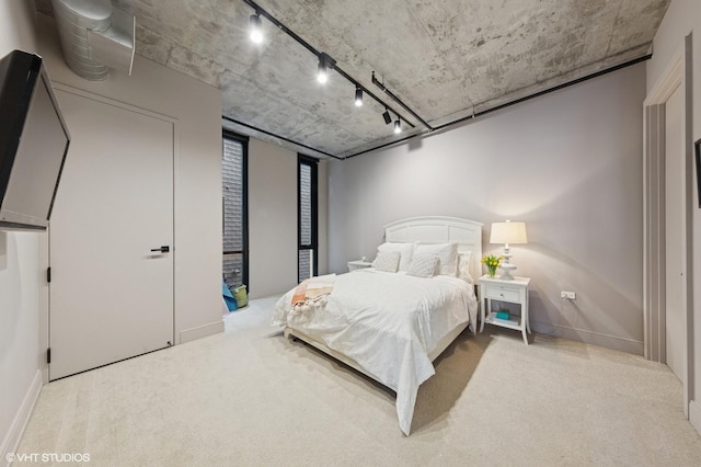 bedroom with carpet floors, rail lighting, and baseboards