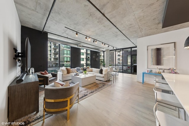 living area with expansive windows, wood finished floors, and track lighting